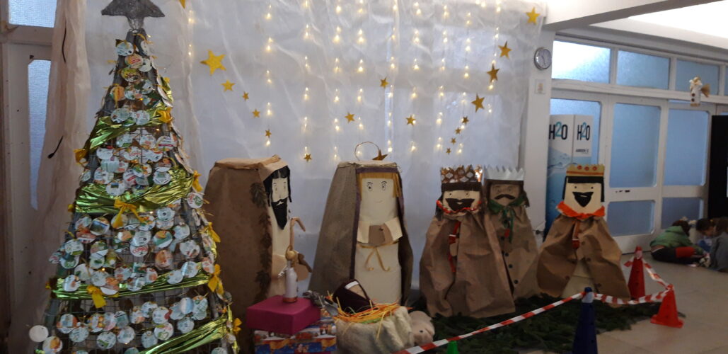 Árvore de Natal no hall de entrada da escola, num arranjo composto também por um presépio, tudo feito com materiais reutilizáveis.