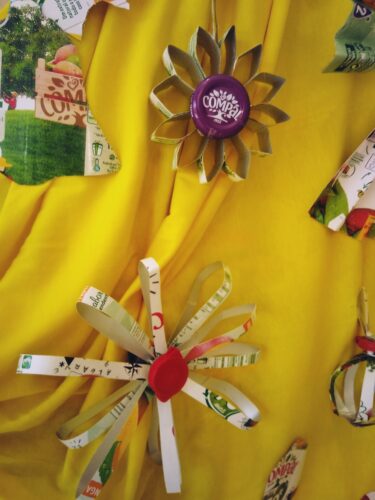 "Enfeites em forma de flor-estrela" - Para enfeitar a árvore de Natal os alunos elaboraram alguns enfeites em forma de flor que lembram uma estrela. Para fazer o centro da flor foram usadas as tampas de embalagens de sumo Compal.