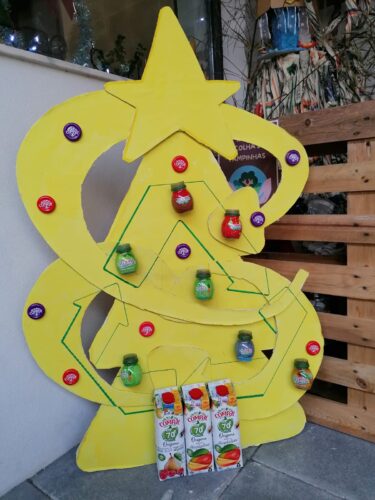 Pormenor da árvore de Natal Amarela: embalagens tetrapak, embalagens da compal, tampas dos frascos da compal, e símbolo da reciclagem incorporado.