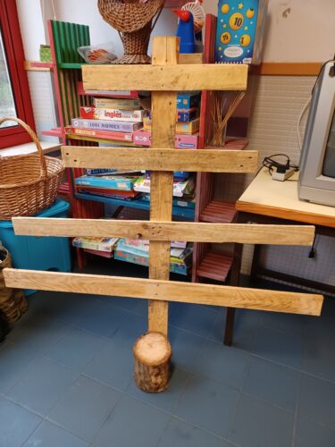 Estrutura da árvore, previamente preparada pelas professoras, com madeira de paletes e um tronco de madeira para lenha.