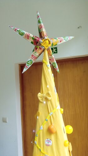 Pormenor do topo da árvore - estrela elaborada com embalagens Compal e meias amarelas.